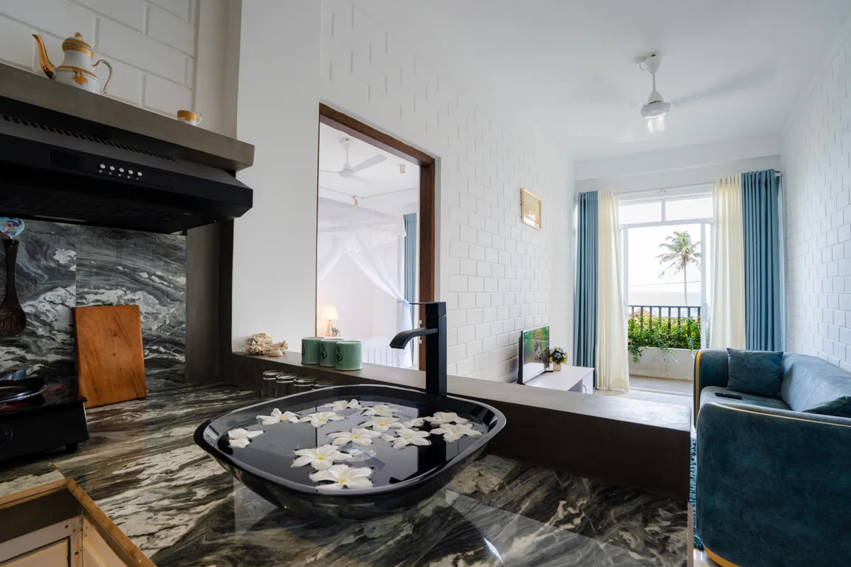 Suite kitchen with a flower-filled bowl, blue sofa and a balcony overlooking the sea at Bliss Blessings Villa & Spa